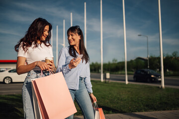 Young shopper girls with shopping bags walking at shopping center.