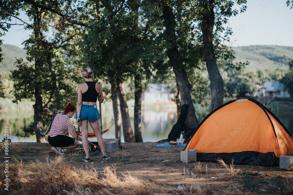 Wall mural two friends camping and enjoying a picnic by a tent in a scenic mountain setting, surrounded by tree