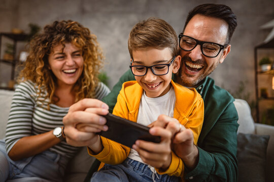 mum, dad and son play video games together on mobile phone at home