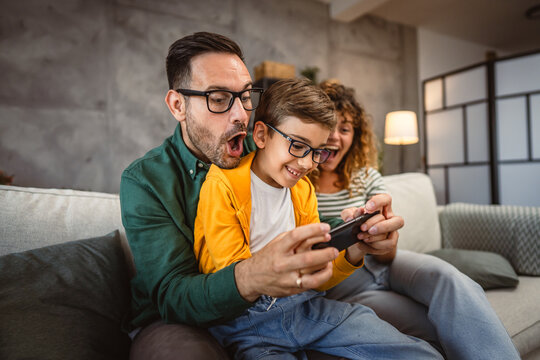 mum, dad and son play video games together on mobile phone at home