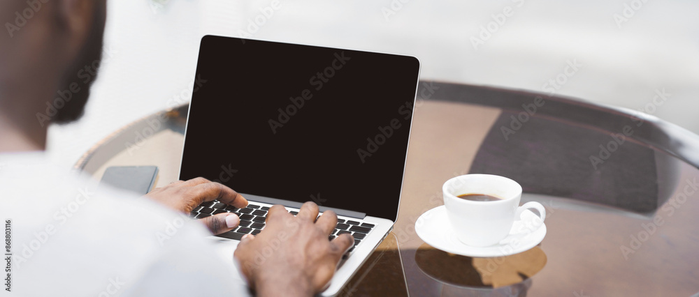 Aufkleber a close-up view of a mans hands typing on a laptop with a cup of coffee in the background.