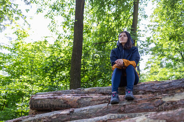 Fototapeta premium Woman tourist sitting on tree logs in the forest.
