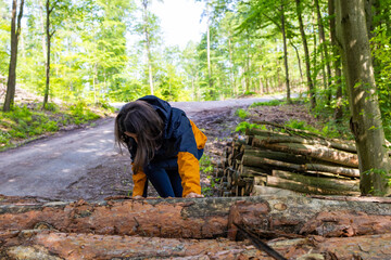  Woman tourist climbs up the wooden logs in the forest.