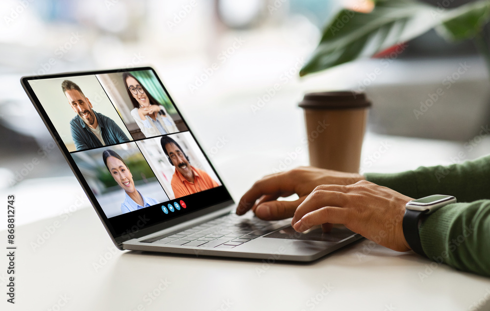 Poster cropped of person is participating in a video conference on a laptop. they are sitting at a table an