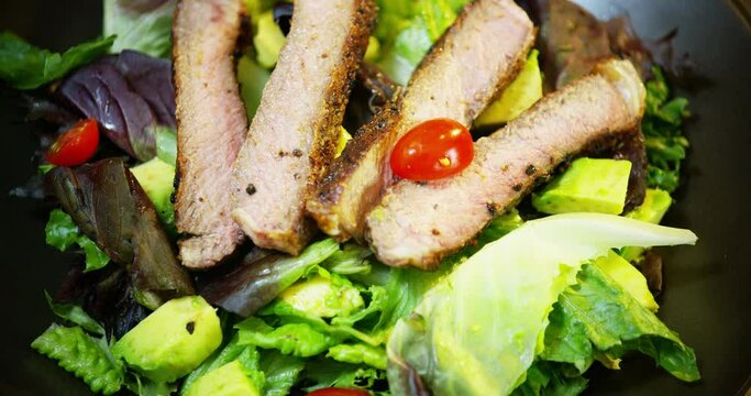 Adding tomato slices to red romaine steak salad
