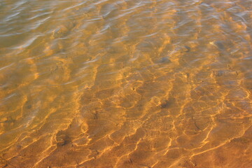 Ripples on the water with sun glare on a sandy shallow