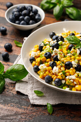 Blueberry Corn Feta Salad in white plate on wooden table. Healthy food