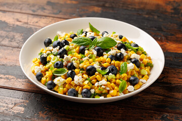 Blueberry Corn Feta Salad in white plate on wooden table. Healthy food