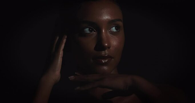 Woman, sensual and glow for skincare portrait with beauty, natural shine and confidence in dark studio. Girl, dermatology and body with skin shimmer, makeup and movement by black background.