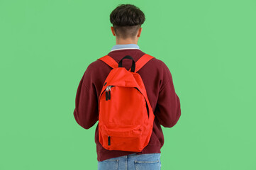 Male student with backpack on green background, back view