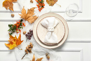 Autumn table setting with sea buckthorn, grapes and dried leaves on white background