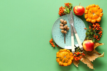 Autumn table setting with pumpkins, apples and sea buckthorn on green background