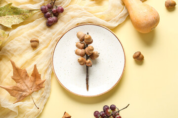 Autumn table setting with pumpkin, grapes and chestnuts on yellow background