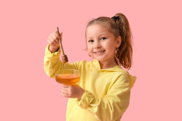 Cute little girl holding bowl with honey on pink background. Rosh Hashanah (Jewish New Year) celebration