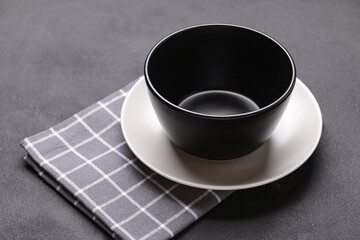 Plate, bowl and napkin on black background