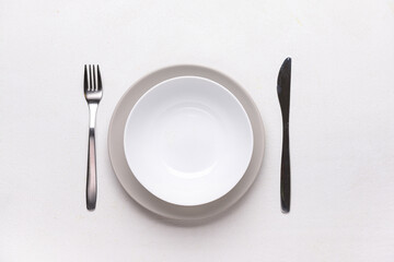 Table setting with clean plates and cutlery on white background
