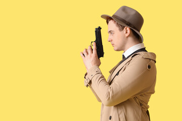 Male spy with gun on yellow background