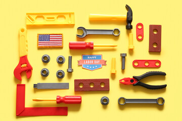 Greeting card with text HAPPY LABOR DAY, USA flag and toy tools on yellow background. Labor Day celebration