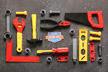 Greeting card with text HAPPY LABOR DAY and toy tools on grey grunge background. Labor Day celebration