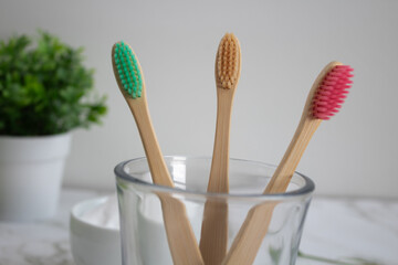 Three bamboo toothbrushes in a glass. Sustainable dental hygiene