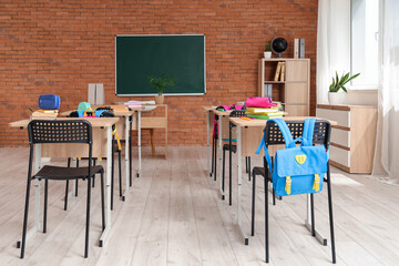 Interior of classroom with chalkboard, desks and backpacks