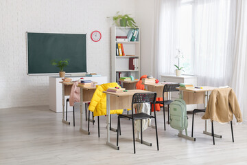 Interior of classroom with chalkboard, desks and shelf unit