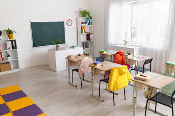 Interior of classroom with chalkboard, desks and shelf units