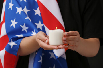 Woman with flag of USA holding burning candle, closeup. National Day of Prayer and Remembrance for...