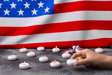 Female hand with burning candles and pinwheel on table against flag of USA. National Day of Prayer...