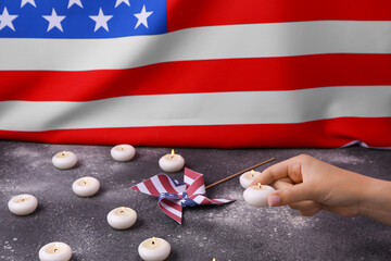 Female hand with burning candles and pinwheel on table against flag of USA. National Day of Prayer...