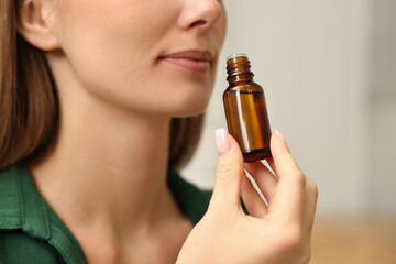 Fototapeta premium Aromatherapy. Woman with bottle of essential oil on light background, closeup