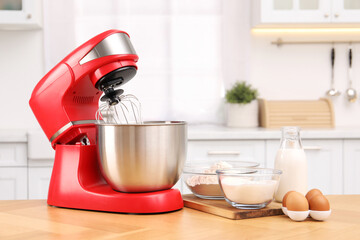 Modern red stand mixer and products on wooden table in kitchen