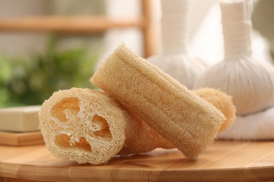 Loofah sponges on wooden table indoors, closeup