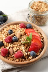 Tasty granola with berries, nuts and mint on white table