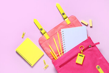 School backpack and different stationery on pink background