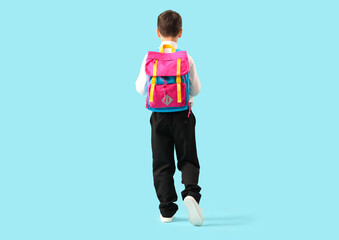 Little schoolboy with backpack on blue background, back view