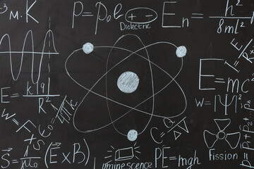 Drawn atomic structure and physics formulas on black chalkboard