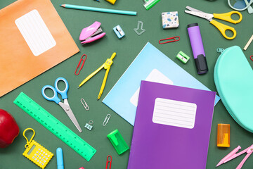 School supplies with copybook, scissors and dividers on green background. Top view