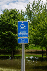 Handicap Parking Sign Closeup Near Park With Trees and Flood Waters