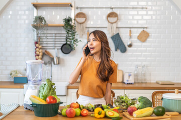 Portrait happy beauty slim healthy asian woman use phone and vegan food healthy fresh vegetable and fruit in kitchen.diet, vegetarian, eating, fruit, wellness, health, green food.Fitness, healthy food