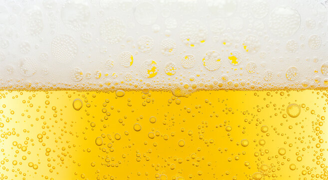 Beer background texture. Close up beer gluss with frothy foam and bubbles