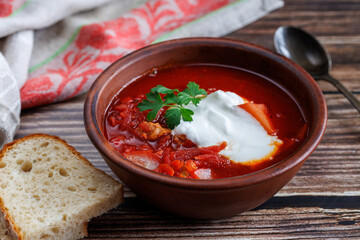 Traditional Ukrainian Russian borscht . Bowl of red beet root soup borsch with white cream with bread on wooden background. Beet Root delicious soup. Traditional Ukraine Russia food cuisine
