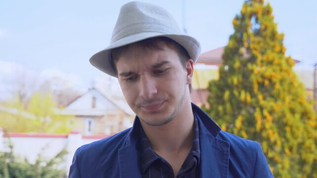 A young man in a blue jacket and fedora standing outdoors with various expressions, showcasing a trendy style