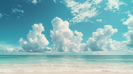 Obraz premium Captured is a tranquil beach scene with bright turquoise waters and cotton-like clouds floating against a clear blue sky, embodying serenity and peacefulness.