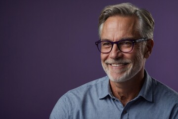 Fototapeta premium Mature man with smile on face next to empty space on dark purple background. Handsome man with space for advertising text.