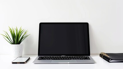 Fototapeta premium Modern laptop computer displaying a blank screen is sitting on a work desk with a smartphone, a plant, and a notebook