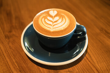A cup of coffee with heart shape latte art on a wooden table