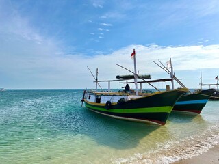 Fototapeta premium Several traditional wooden fishing and passenger boats moored on the beautiful beach in Gili Ketapang, Indonesia