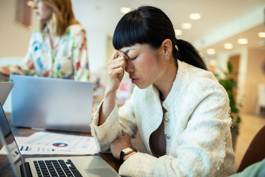 Frustrated Businesswoman with Headache Working on Laptop in Office