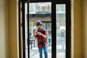 Delivery man checking smartphone while entering building